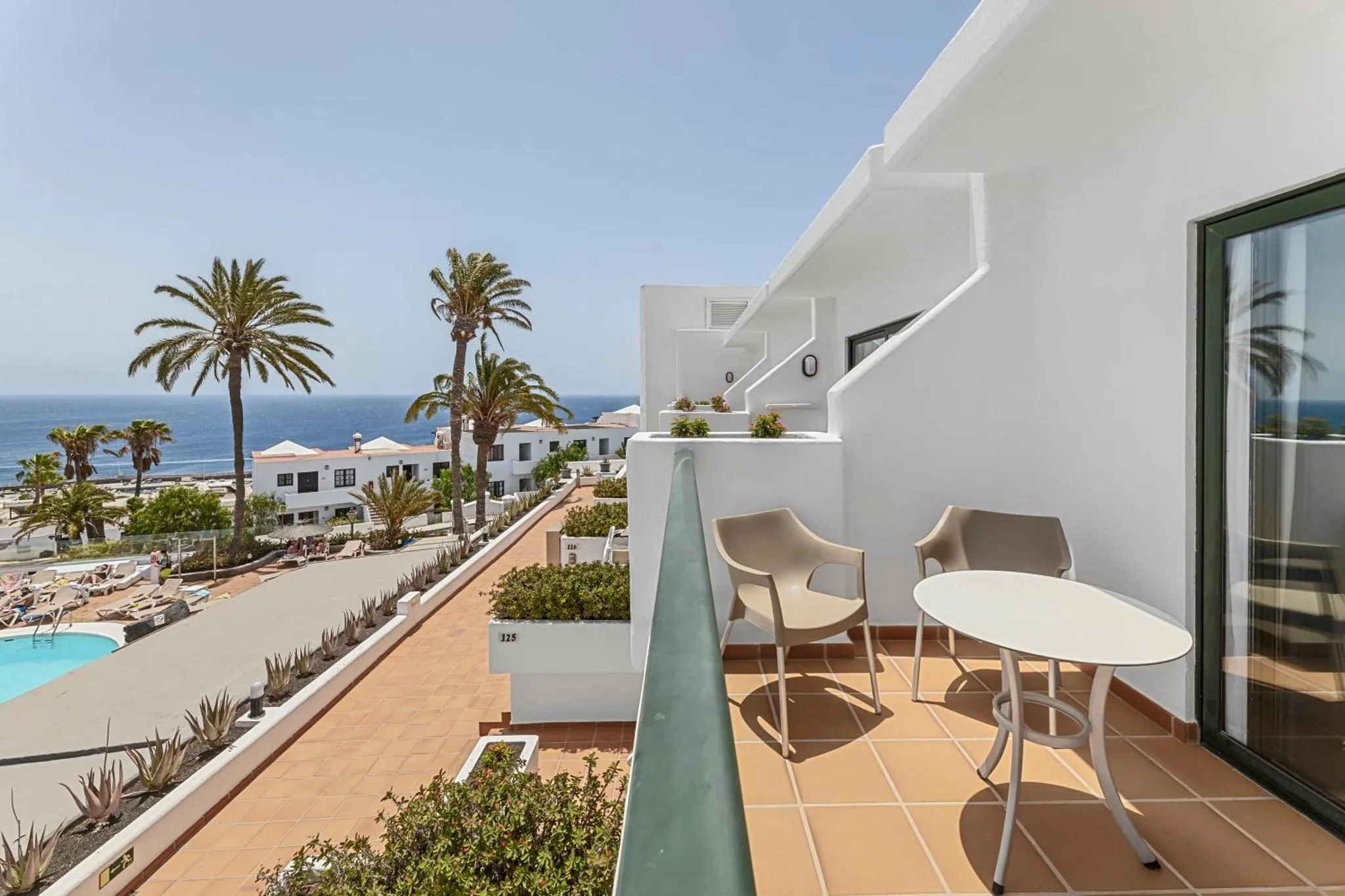 Terrasse avec mobilier d'extérieur donnant sur une vue mer et une piscine.
