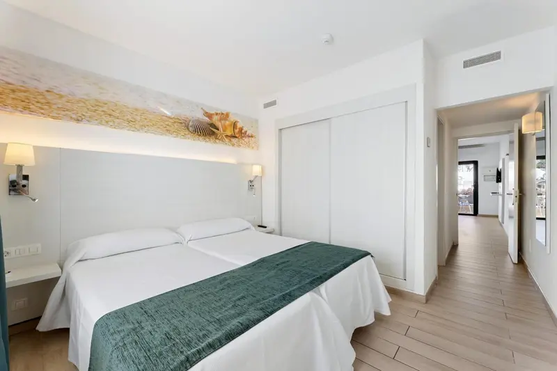 Une chambre lumineuse avec un grand lit et une décoration murale.