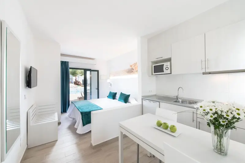 Une chambre lumineuse avec un lit et une kitchenette.
