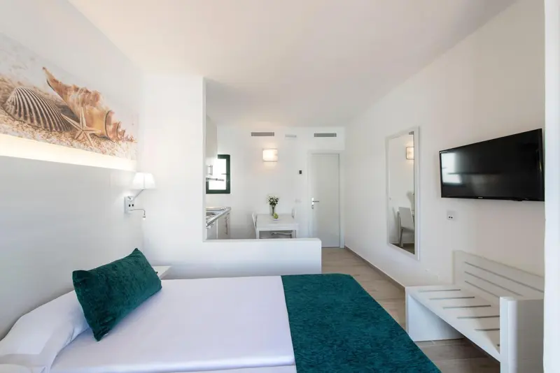 Chambre lumineuse avec un lit recouvert d'une courtepointe turquoise et une décoration murale marine.