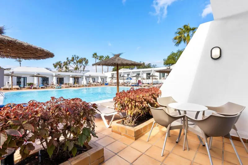 Terrasse avec mobilier d'extérieur donnant sur une piscine ensoleillée.