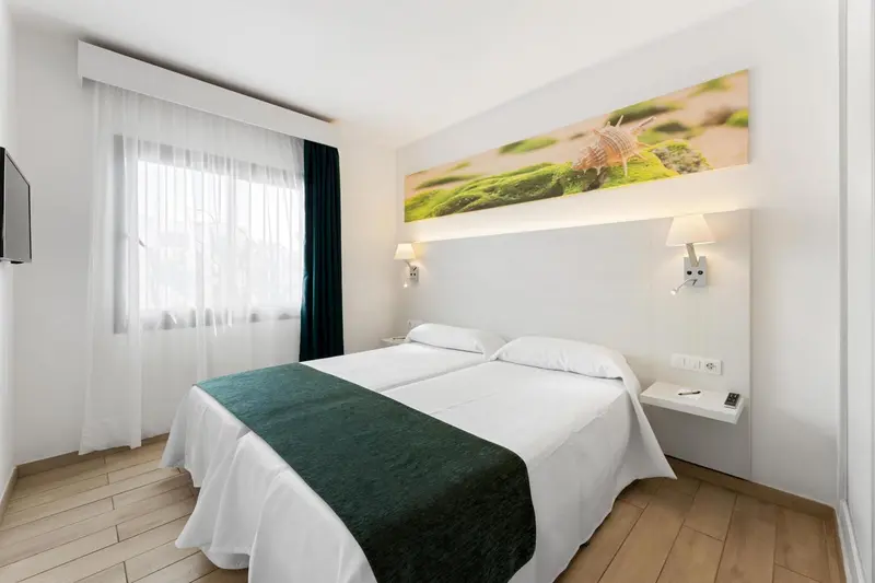 Une chambre lumineuse avec un grand lit et une décoration murale marine.