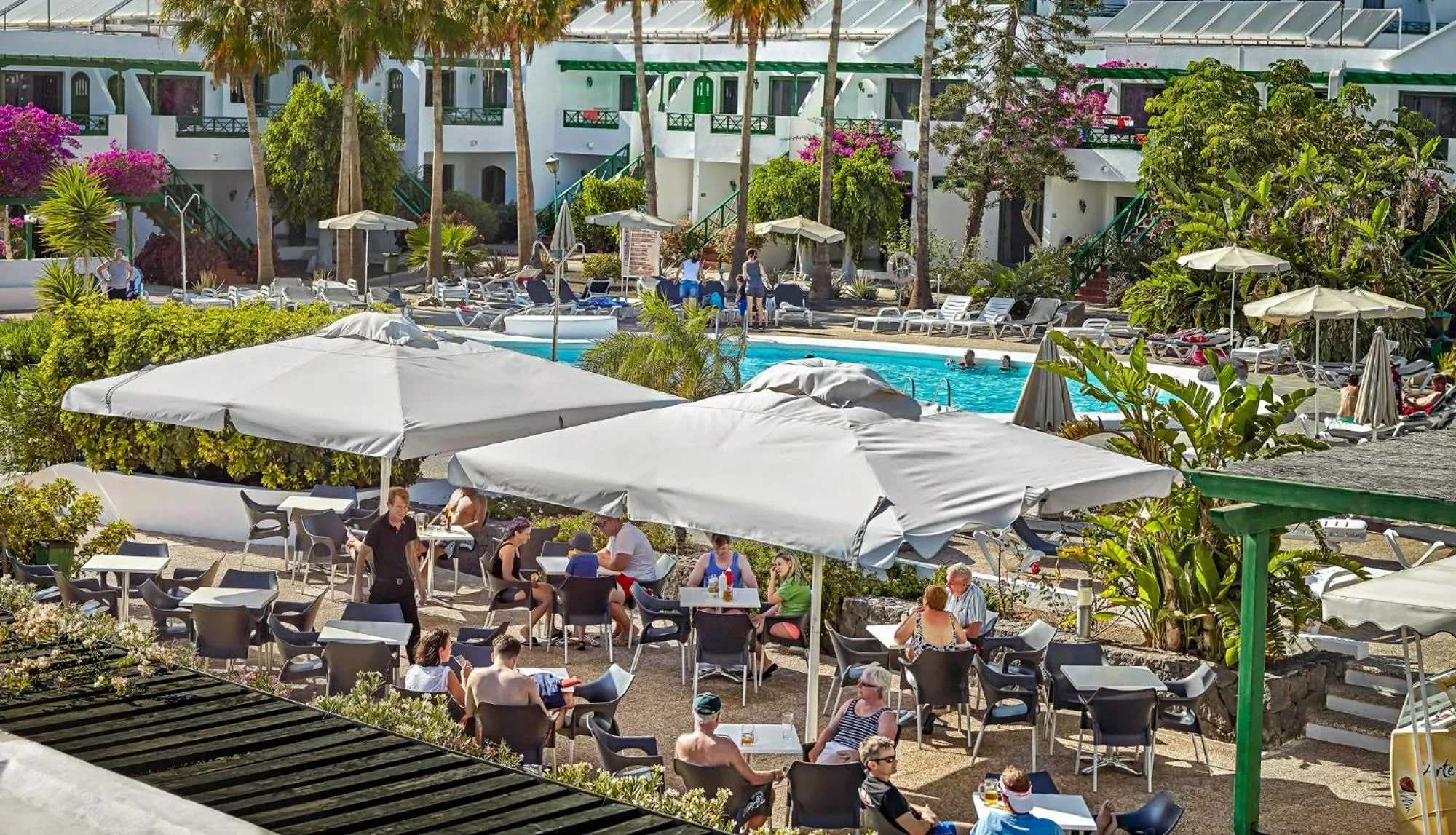 Une terrasse ombragée avec des tables et des chaises accueillant des clients.