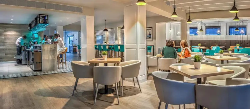 Une salle lumineuse avec des tables et des chaises, et un comptoir de bar.
