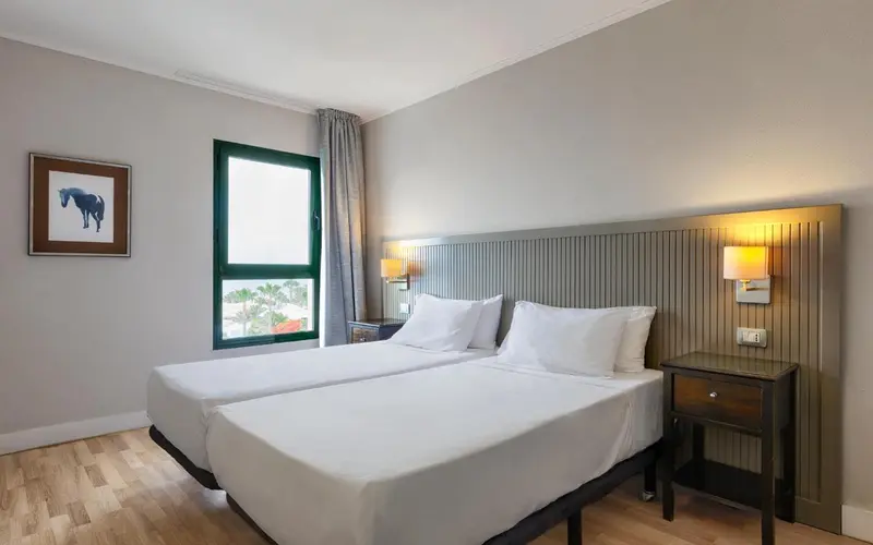Une chambre lumineuse avec deux lits simples et une décoration sobre.
