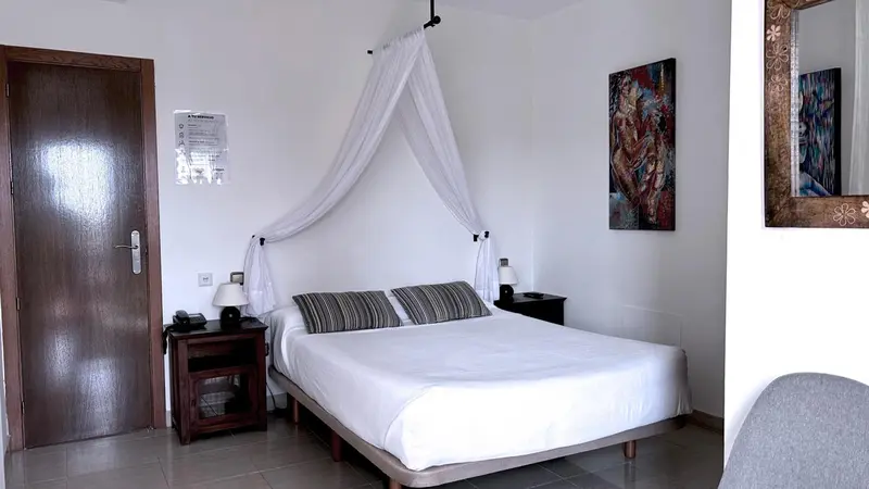 Une chambre lumineuse avec un grand lit à baldaquin et une décoration murale colorée.