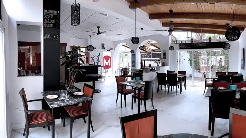 Une salle de restaurant lumineuse avec des tables et des chaises.
