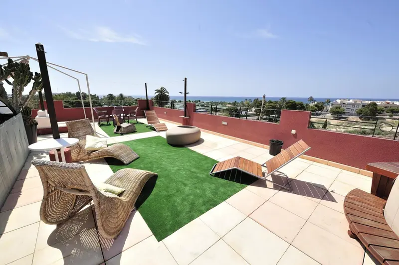 Terrasse aménagée avec mobilier de jardin et vue sur la mer.