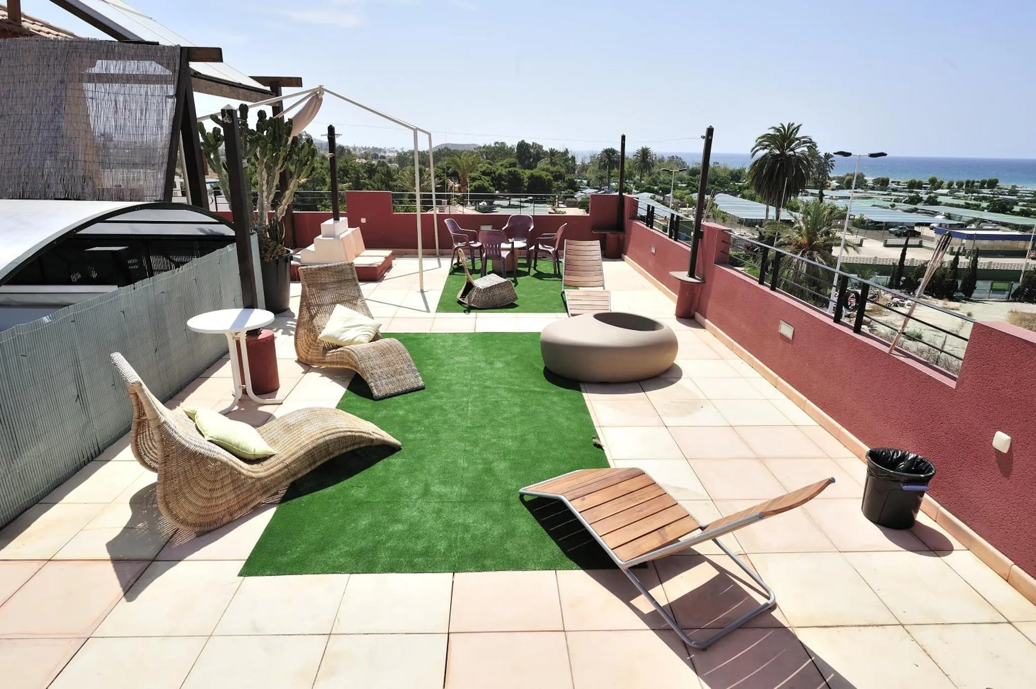 Espace de détente extérieur avec mobilier de jardin et vue sur la mer.