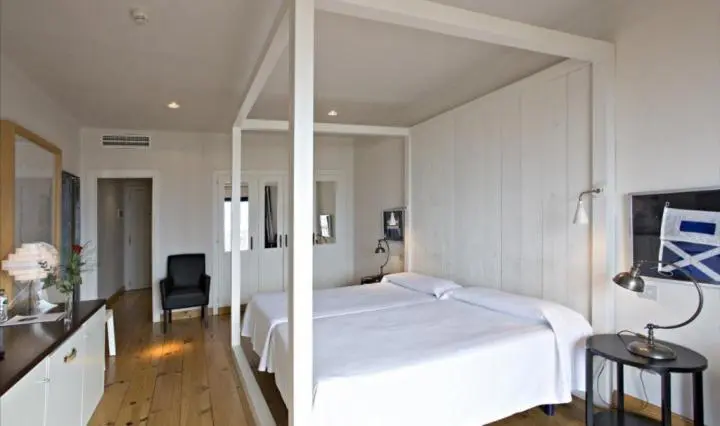 Une chambre lumineuse avec un grand lit à baldaquin et une décoration sobre.