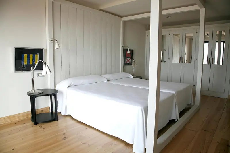 Une chambre lumineuse avec un grand lit à baldaquin et des meubles blancs.