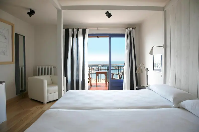 Une chambre lumineuse s'ouvre sur une terrasse avec vue sur la mer.
