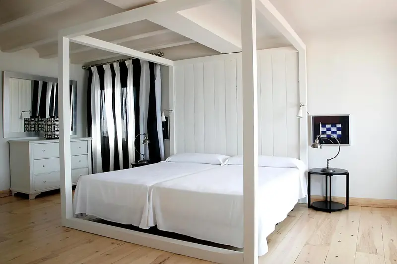 Une chambre lumineuse avec un lit à baldaquin blanc et des rideaux rayés.