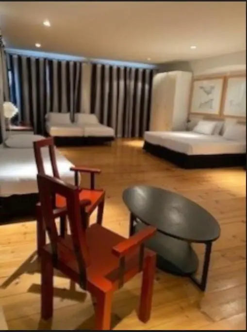 Une pièce lumineuse avec des lits et des fauteuils en bois.