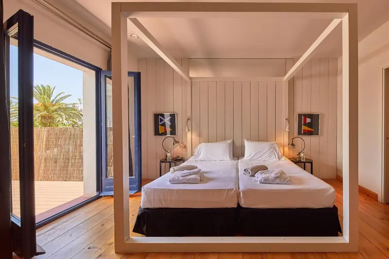 Une chambre lumineuse avec un lit à baldaquin et un accès à une terrasse.