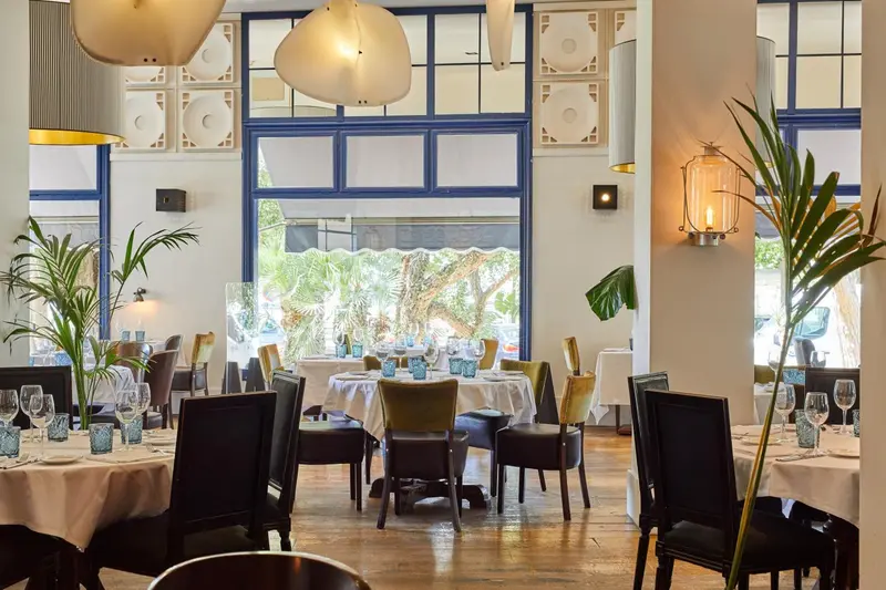 Une salle lumineuse avec des tables dressées pour un repas.
