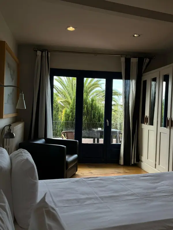 Une chambre lumineuse avec un fauteuil et un accès à une terrasse.