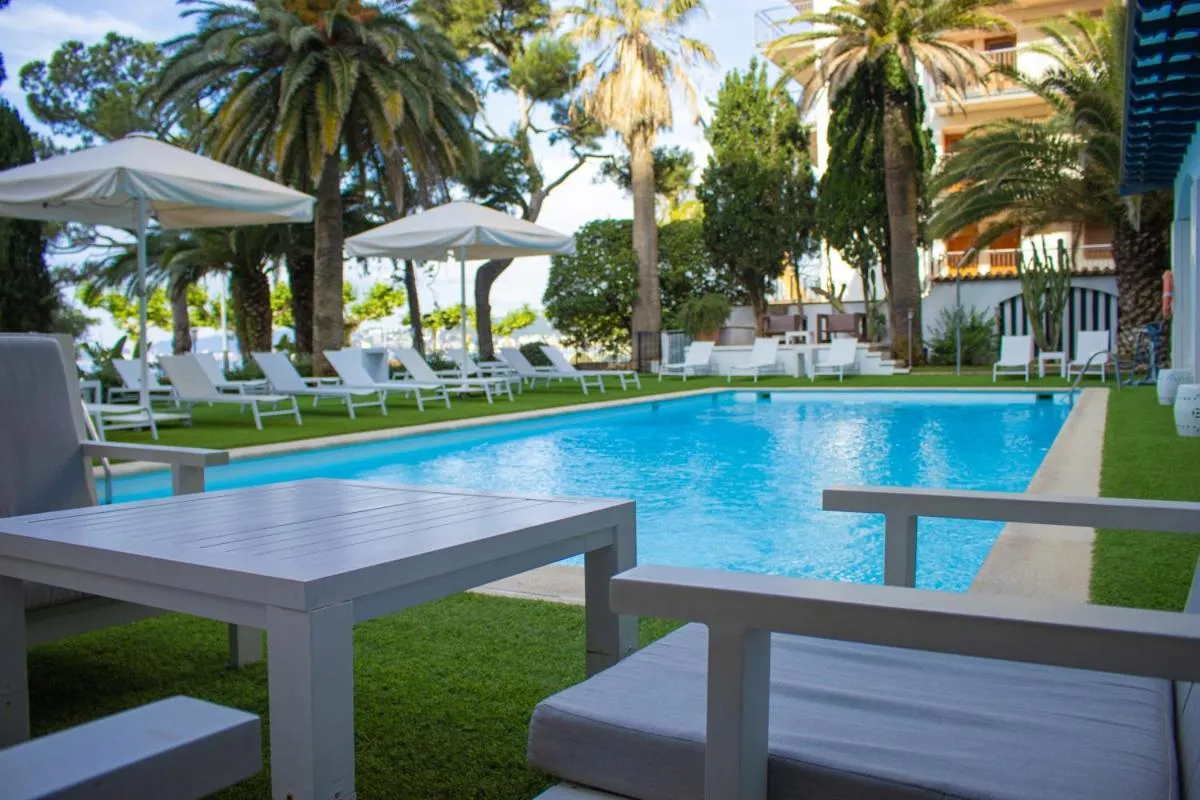 Transats blancs alignés au bord d'une piscine turquoise dans un jardin soigné.