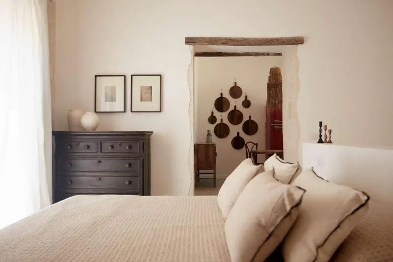 Une chambre lumineuse avec un lit fait et une commode sombre.