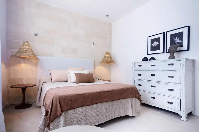 Une chambre lumineuse avec un grand lit et une commode blanche.