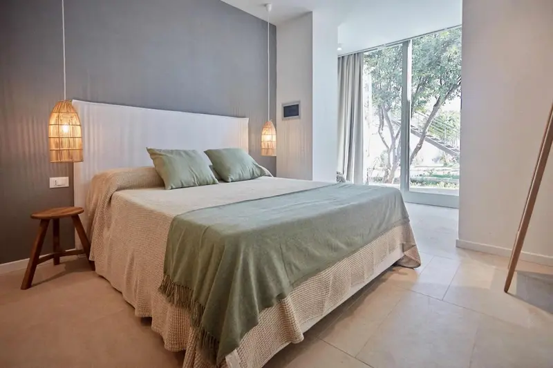 Une chambre lumineuse avec un grand lit et une vue sur la végétation.