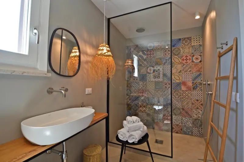 Une salle de bain moderne avec une douche à l'italienne décorée de motifs colorés.