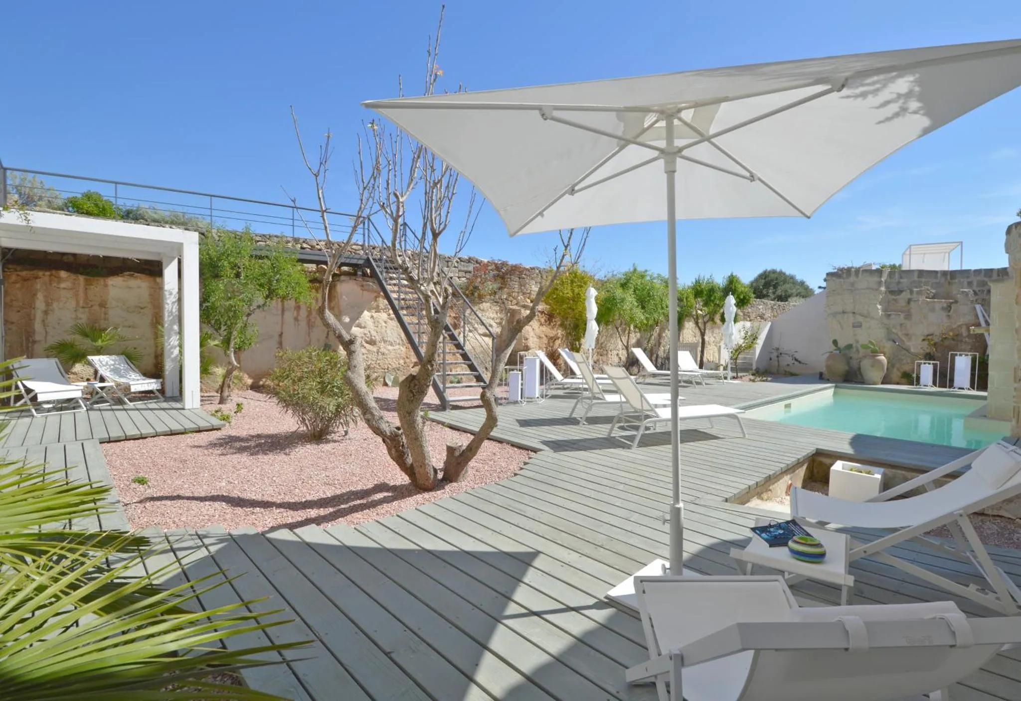 Terrasse avec transats et piscine ensoleillée.