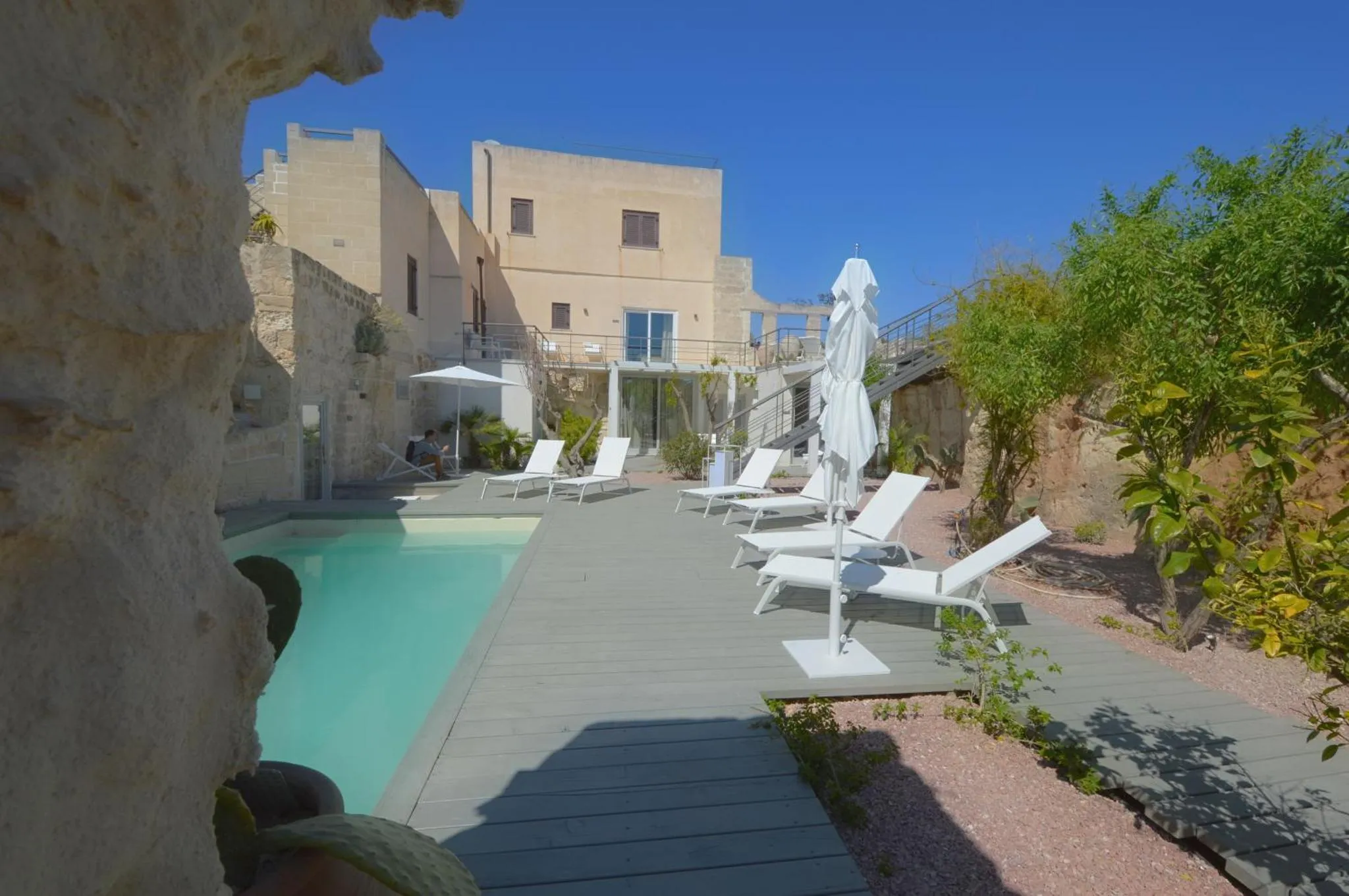 Terrasse avec transats et piscine dans un espace extérieur ensoleillé.