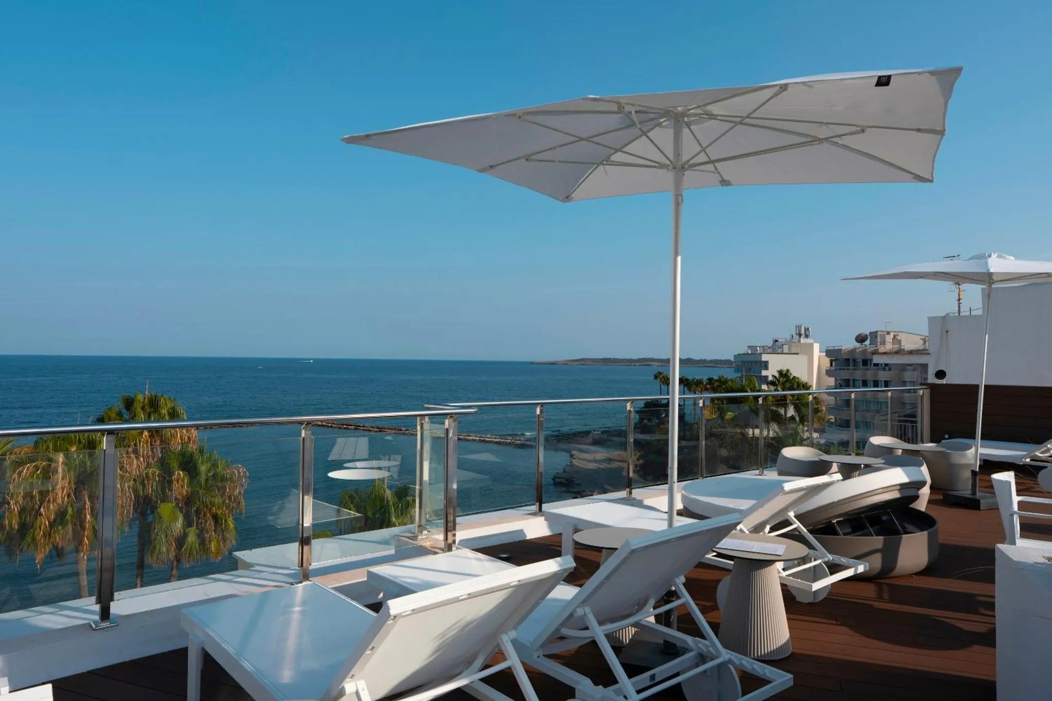 Terrasse avec transats blancs et vue sur la mer.