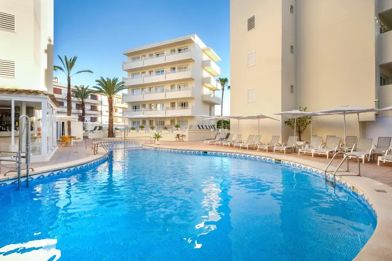 Piscine d'hôtel avec transats et bâtiments en arrière-plan.