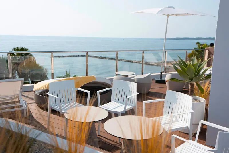 Terrasse aménagée avec mobilier blanc offrant une vue sur la mer.
