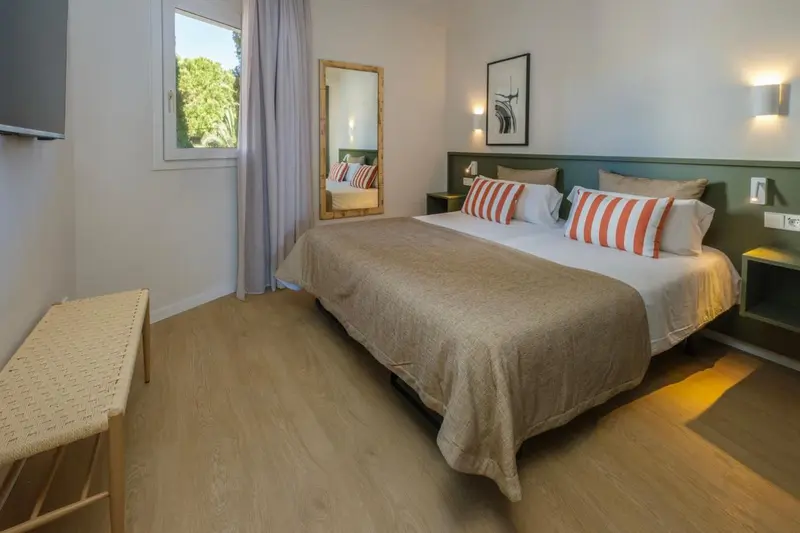 Une chambre lumineuse avec un grand lit et un miroir.