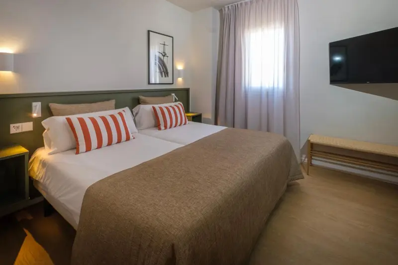 Une chambre lumineuse avec un grand lit et une décoration sobre.