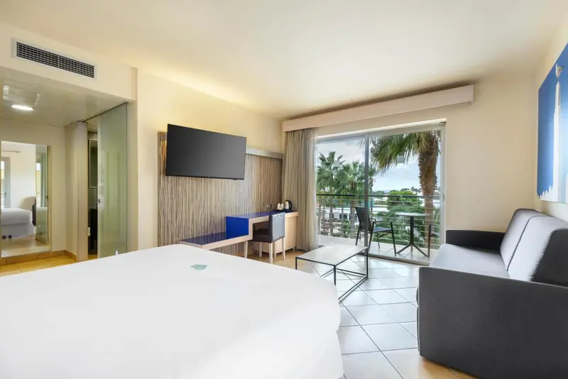 Une chambre lumineuse avec un lit, un canapé et un accès à une terrasse.