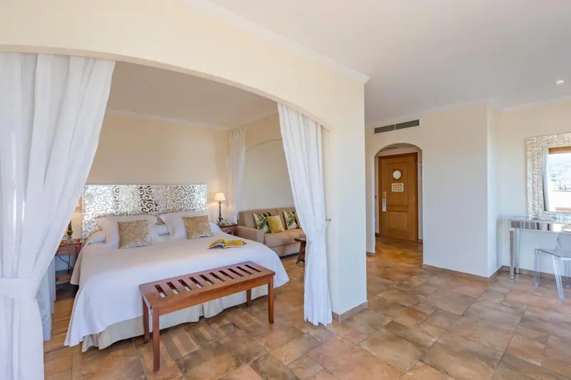 Une chambre lumineuse avec un lit à baldaquin et un coin salon.