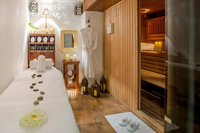 Espace de relaxation avec table de massage et sauna en bois.