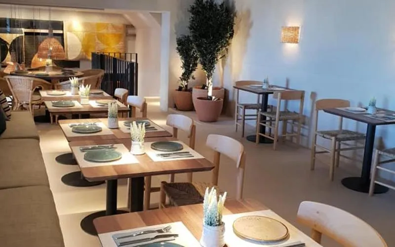 Une salle lumineuse avec des tables dressées pour un repas.