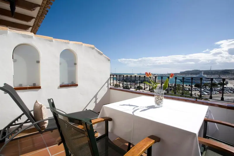 Terrasse avec mobilier d'extérieur et vue sur un port de plaisance.