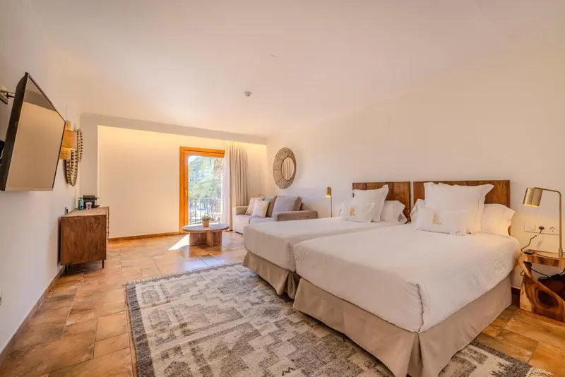 Une chambre lumineuse avec deux lits simples et un coin salon.