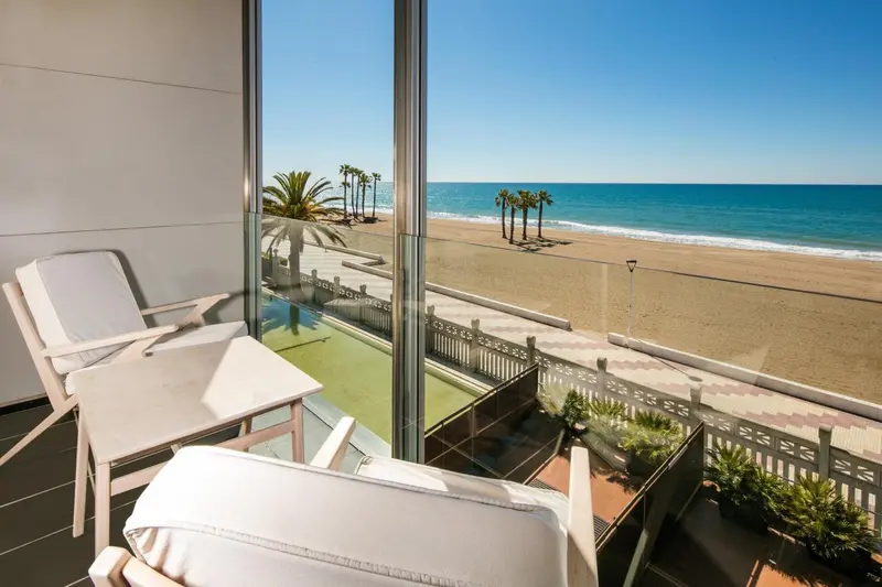 Vue sur une plage de sable fin depuis un balcon aménagé.