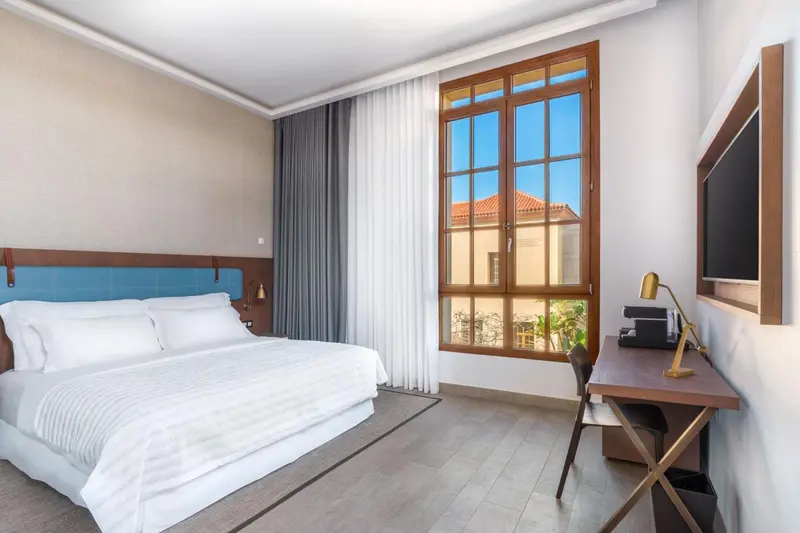 Une chambre lumineuse avec un grand lit et un bureau.