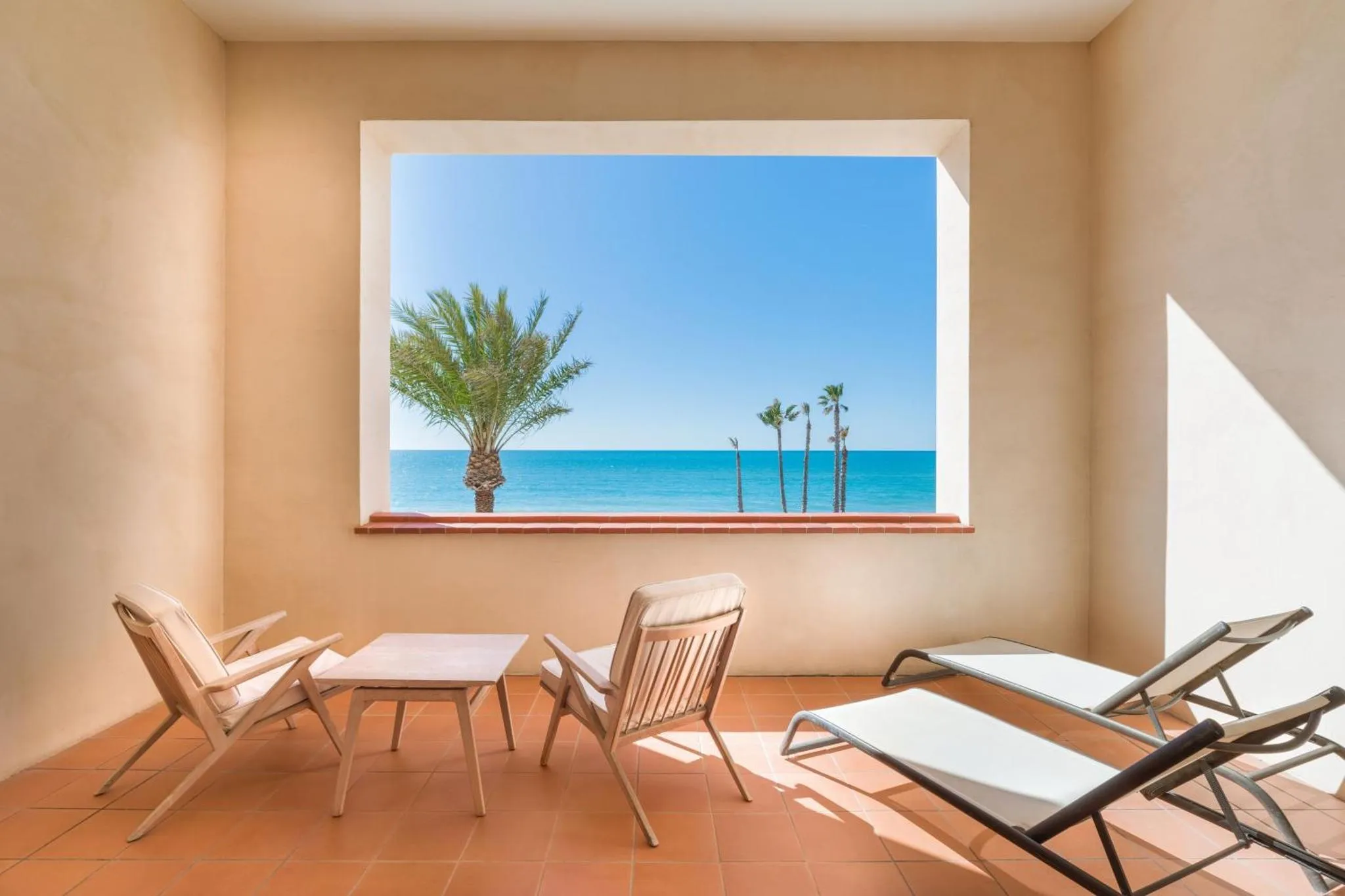 Espace de détente intérieur avec vue sur la mer et la végétation.