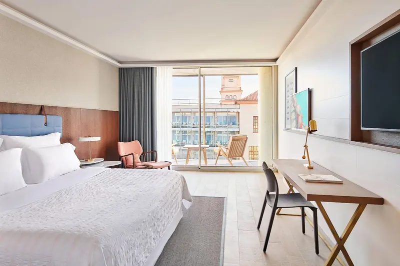 Une chambre lumineuse avec un grand lit et un accès à une terrasse.