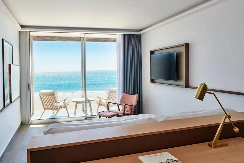 Une chambre lumineuse avec vue sur la mer depuis un balcon.