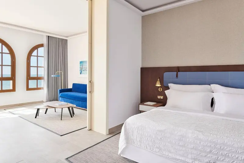 Une chambre lumineuse avec un grand lit et un canapé bleu.