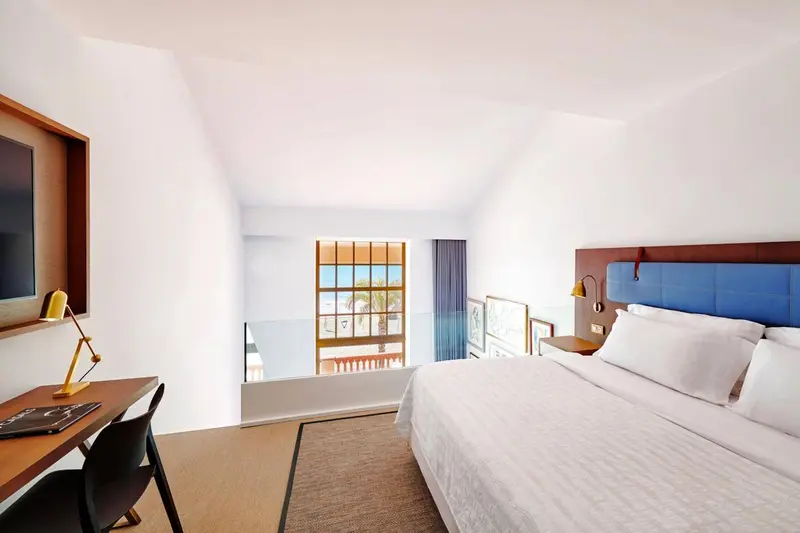 Une chambre lumineuse avec un lit double et un espace bureau.