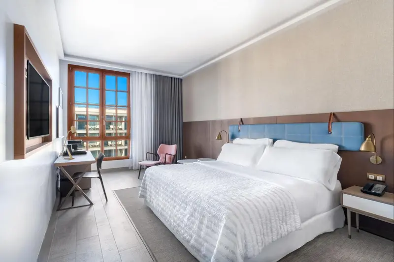 Chambre lumineuse avec un grand lit et une fenêtre donnant sur l'extérieur.
