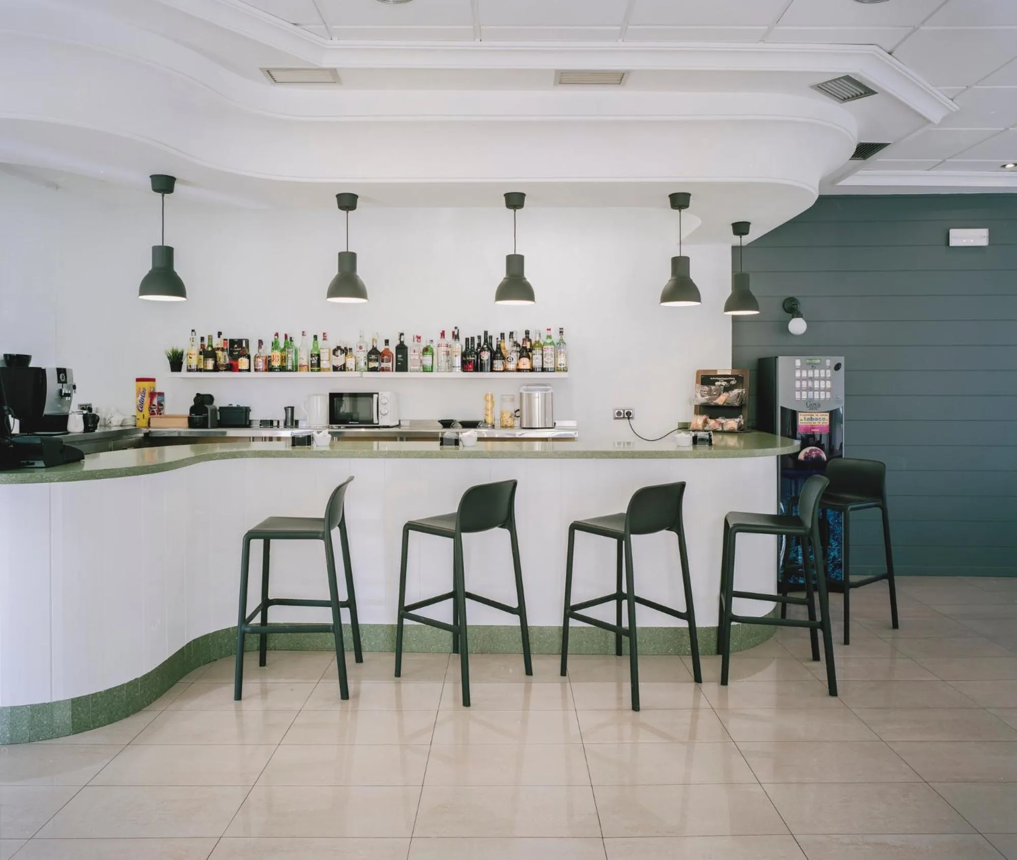 Un comptoir de bar moderne avec des tabourets hauts et une sélection de boissons.