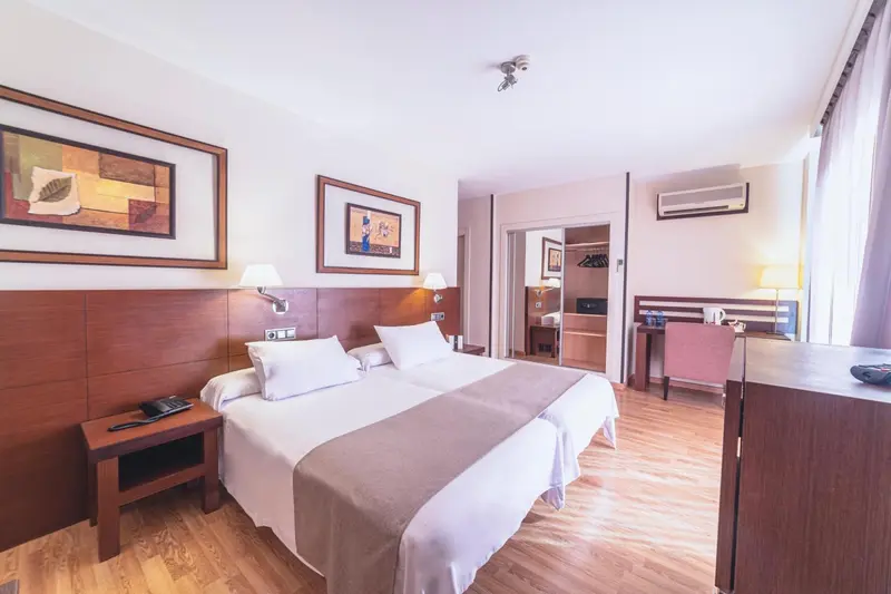 Une chambre d'hôtel lumineuse avec un grand lit et une décoration sobre.