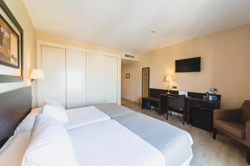 Une chambre d'hôtel lumineuse avec un lit double et un espace bureau.